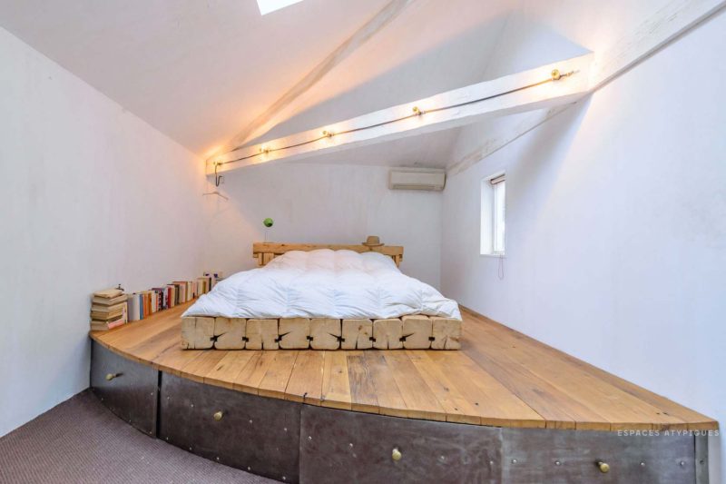 Chambre avec lit sur un estrade en bois avec rangements
