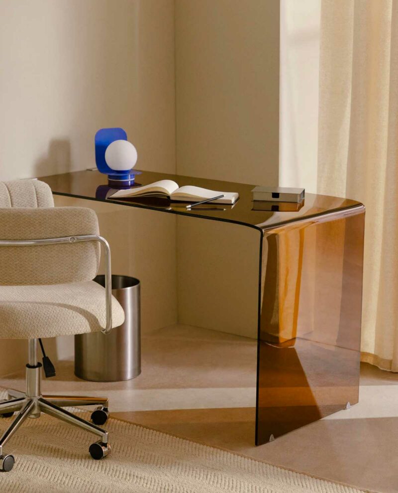 Un bureau en verre fumée fixé contre un mur