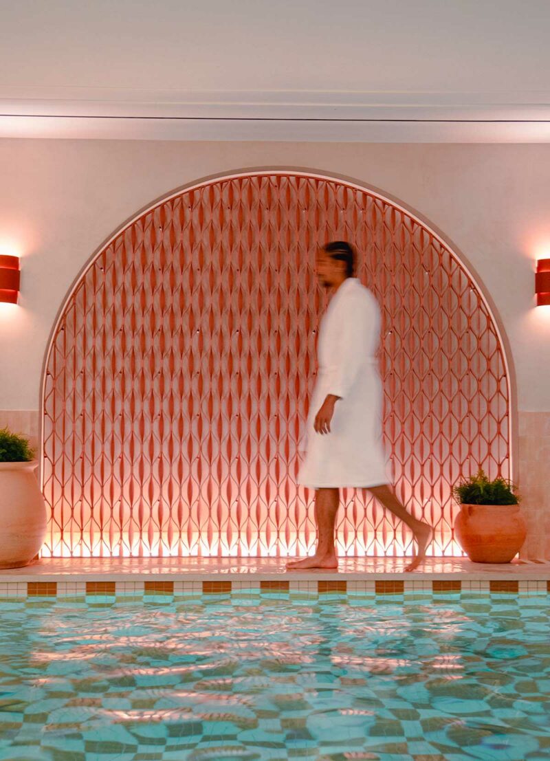 Homme en peignoir kimono Narumi Madura blanc marchant au bord d'une piscine dans un espace spa