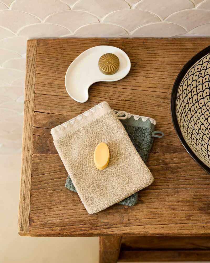 Gants de toilette Neryda Madura en beige et vert séquoia avec un savon sur table en bois
