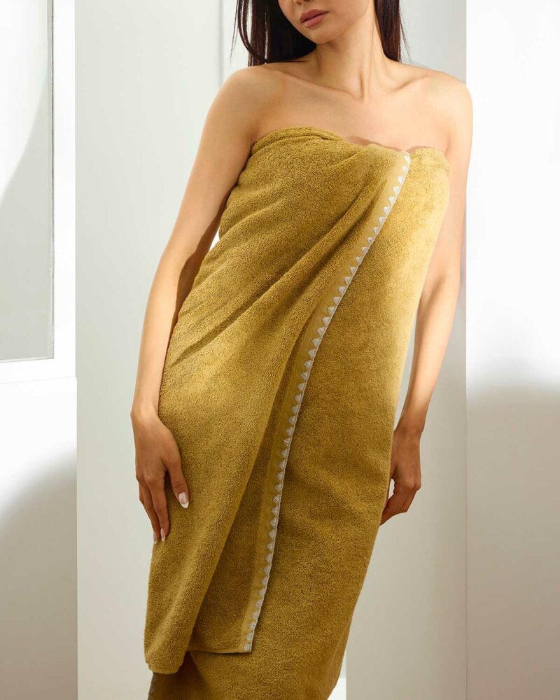 Femme enveloppée dans une serviette de bain Neryda Madura en jaune sable, point de feston visible