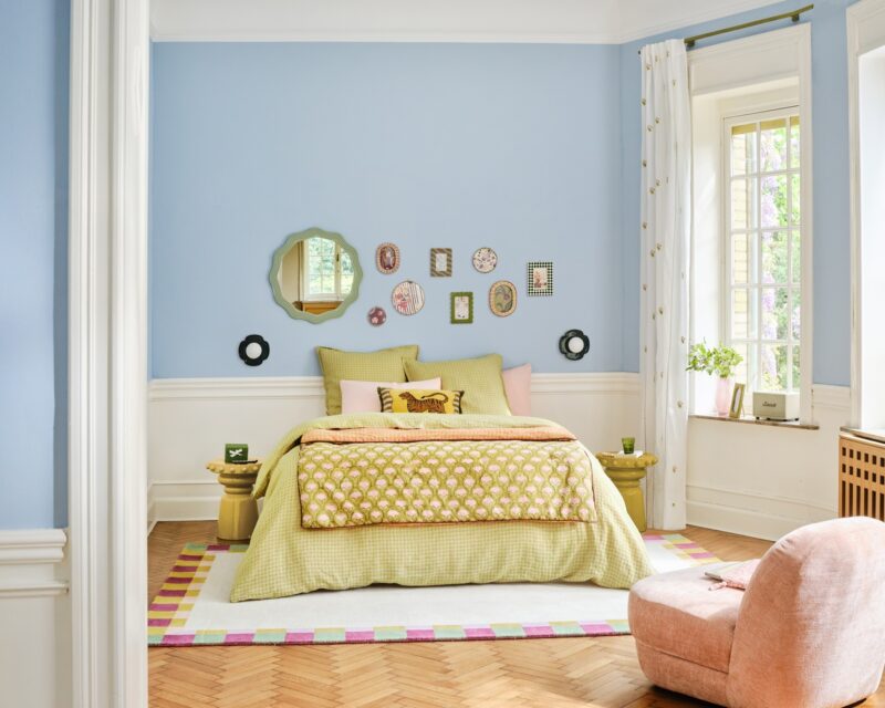 Chambre Blossom Twist aux murs bleus avec assiettes décoratives et miroir